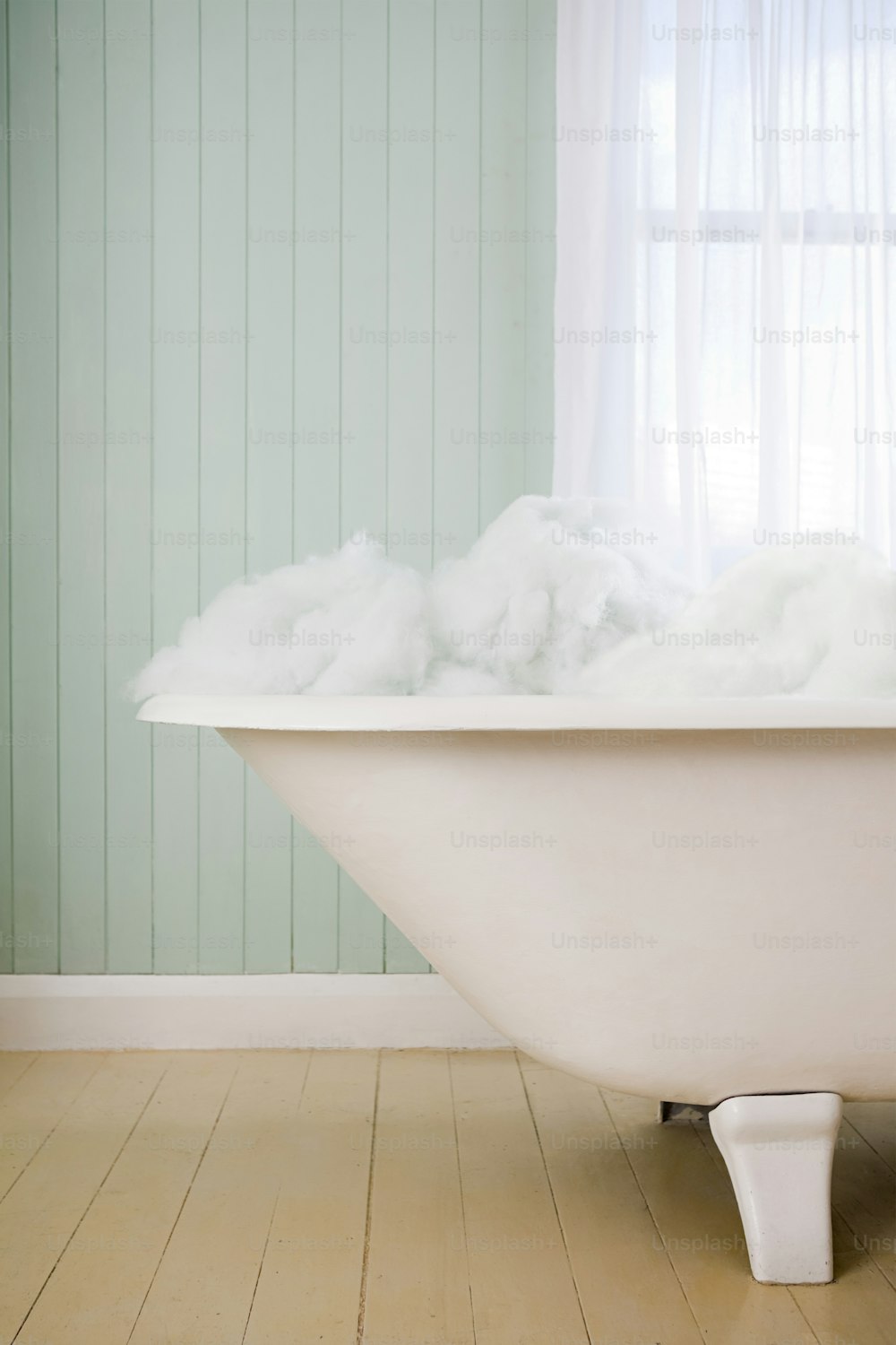 a bathtub filled with foam on top of a wooden floor