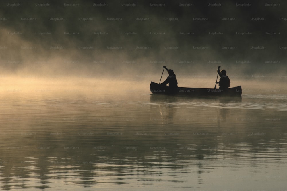 two people in a canoe paddling on a foggy lake