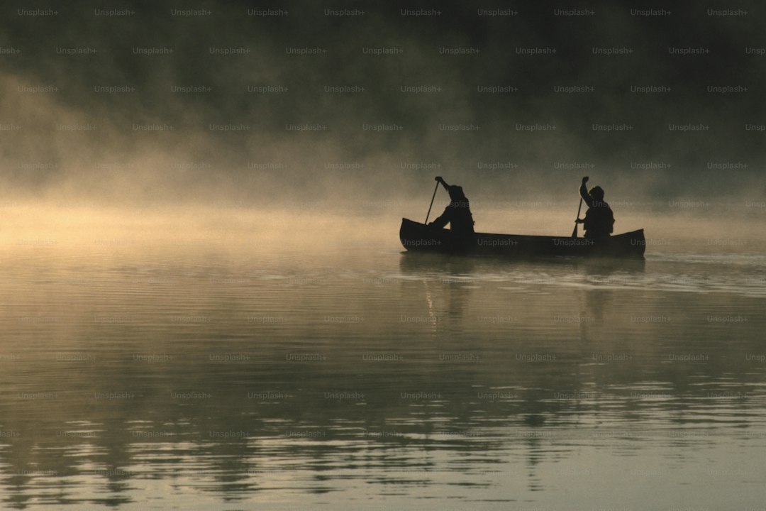 two people in a canoe paddling on a foggy lake
