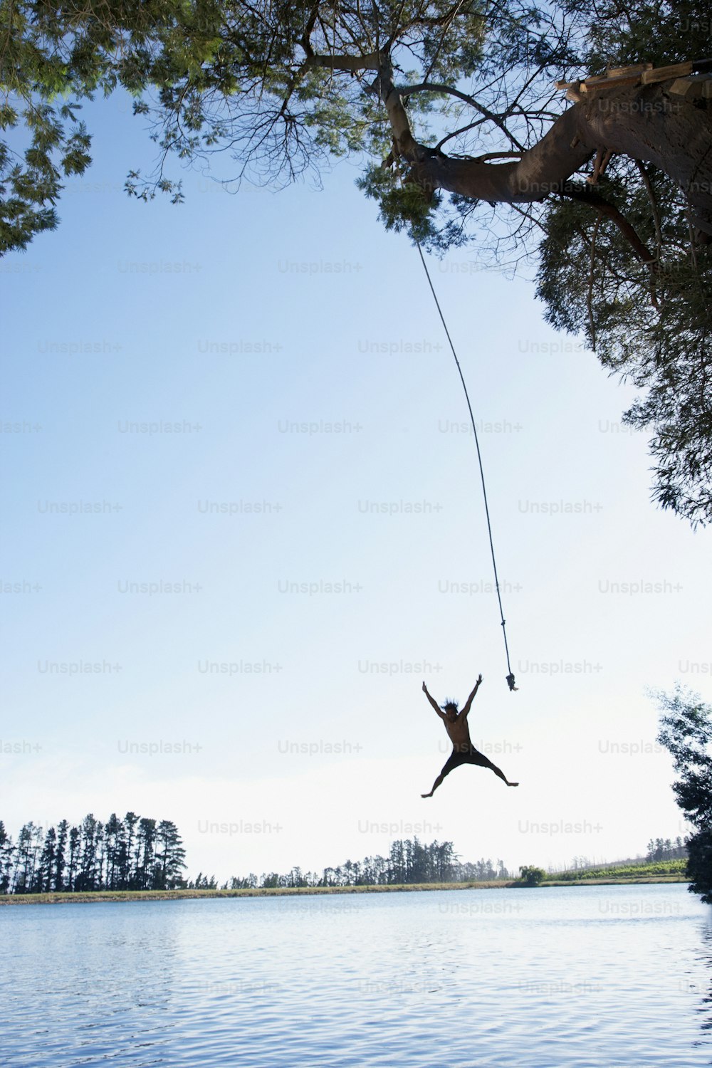 a man is hanging from a rope over a body of water