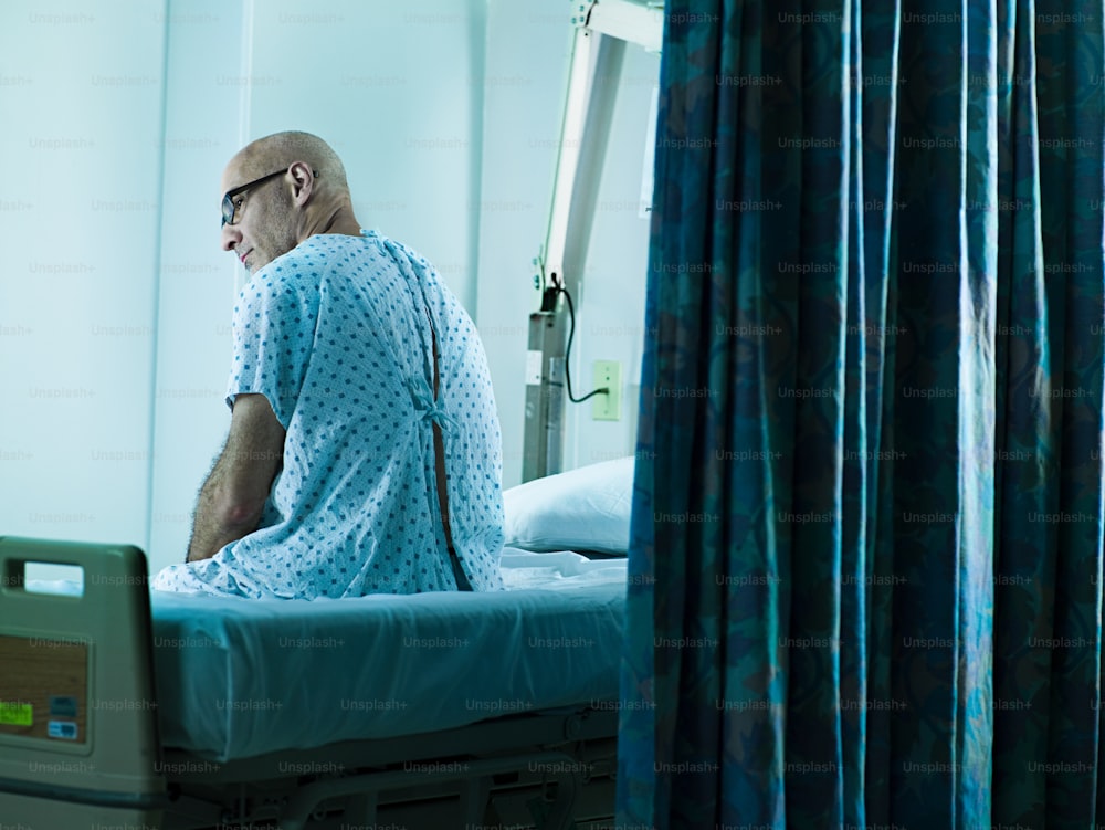 a man in a hospital gown sitting on a hospital bed