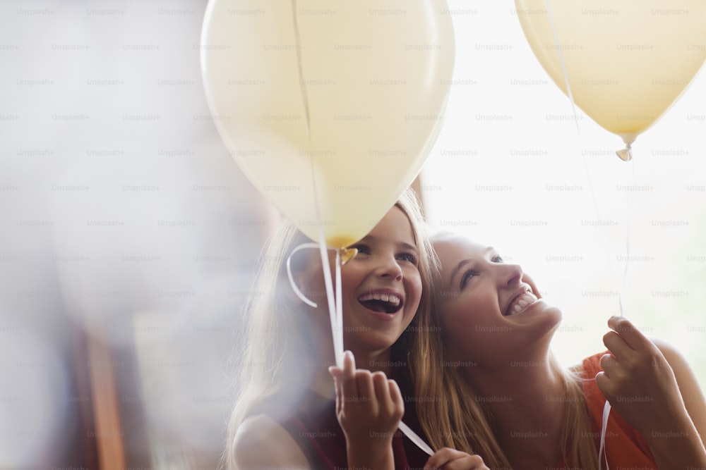 two girls are laughing while holding balloons