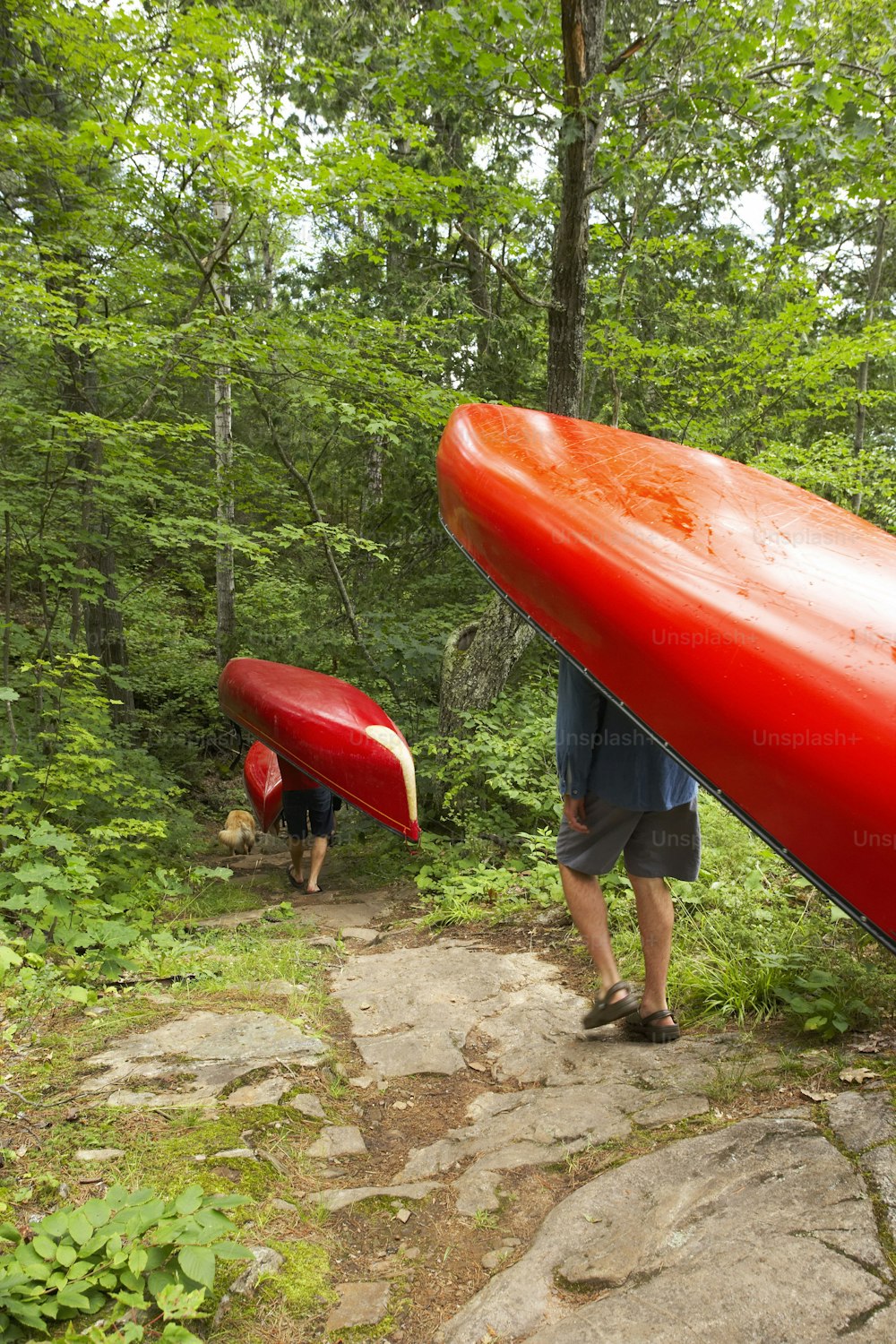 a man carrying a red canoe up a hill