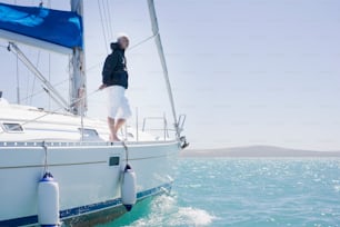 a man standing on a sailboat in the ocean