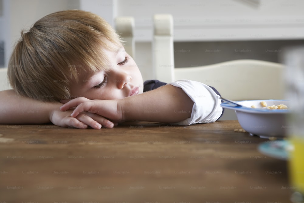 a young boy laying his head on a table
