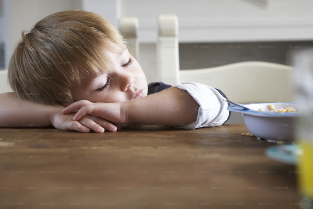 a young boy laying his head on a table