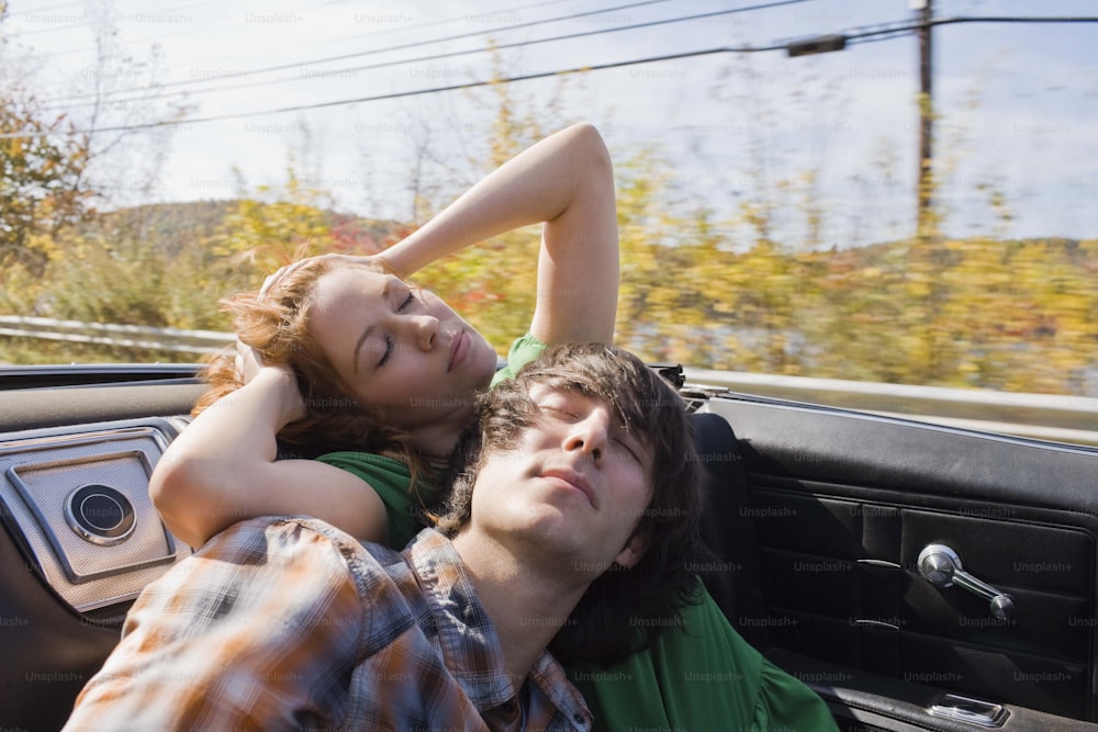 a man and a woman laying in the back of a car