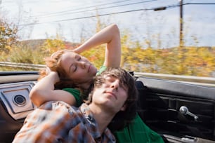 a man and a woman laying in the back of a car