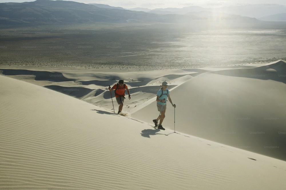 a couple of people riding skis across a desert