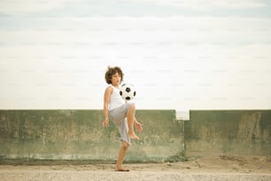 a young boy kicking a soccer ball up into the air