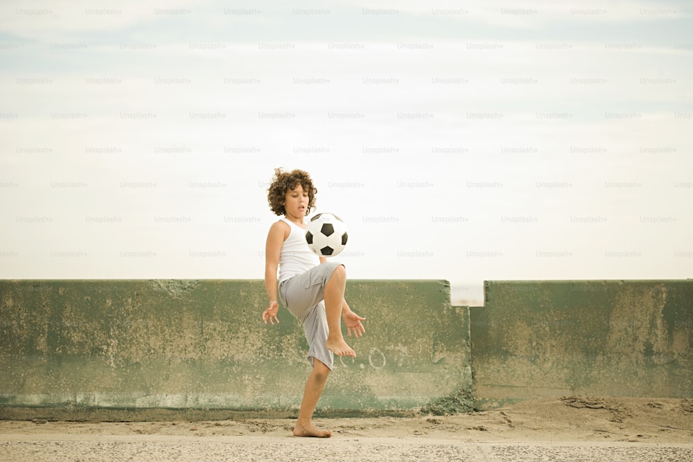 a young boy kicking a soccer ball up into the air