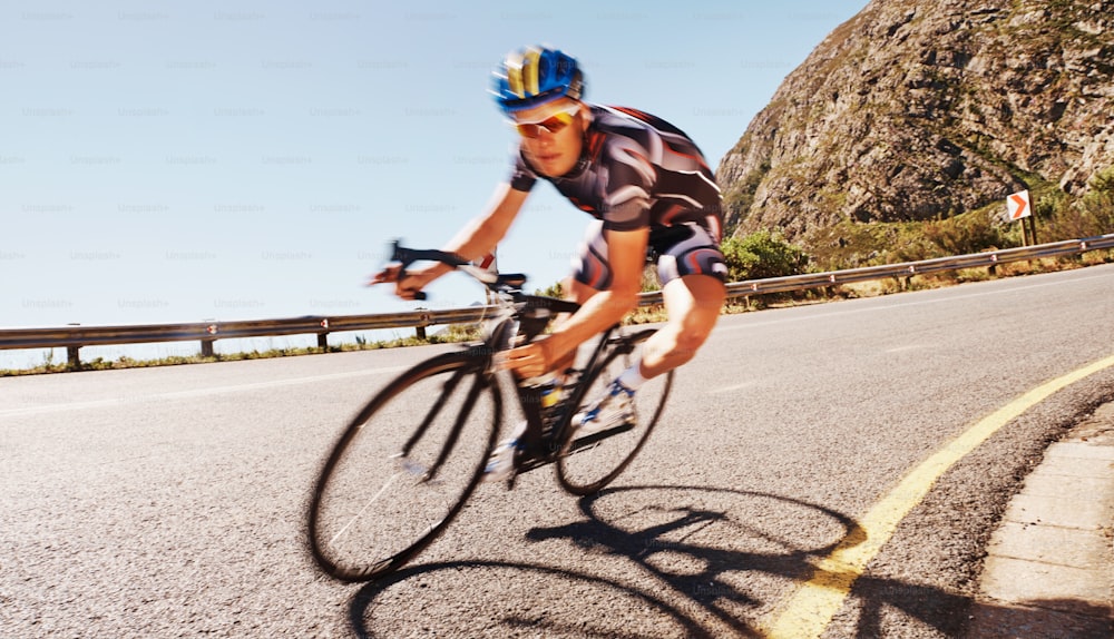 Foto de um ciclista solitário correndo ladeira abaixo em uma estrada rural