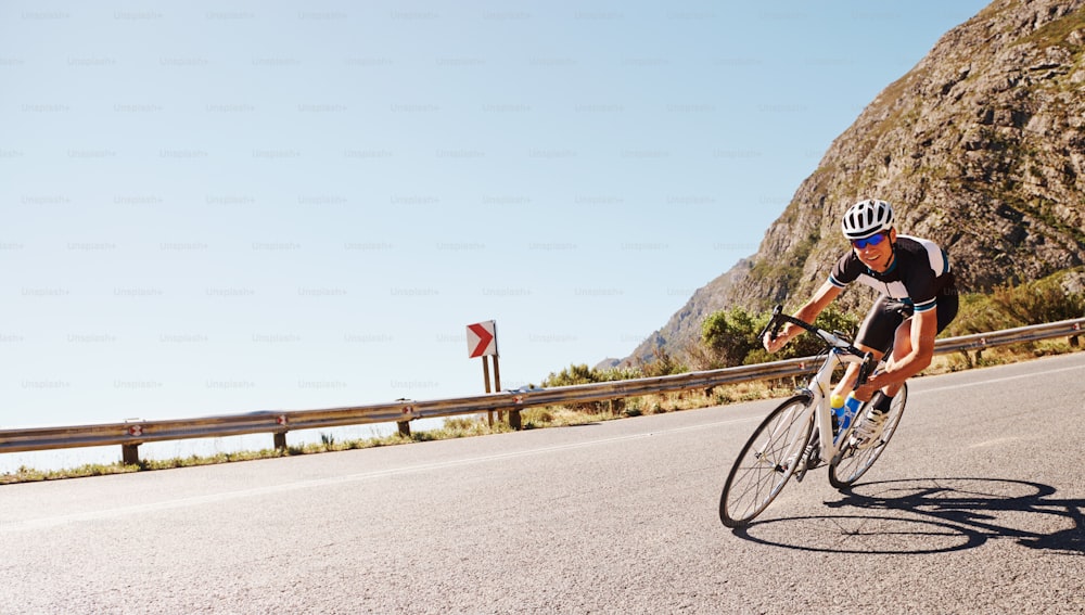 Plan d’un cycliste solitaire dévalant une pente à toute vitesse sur une route de campagne