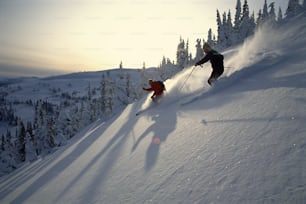 a couple of people riding skis down a snow covered slope