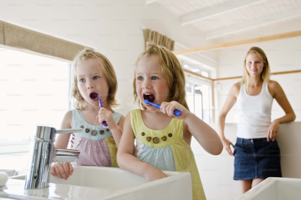 two young girls brushing their teeth in a bathroom
