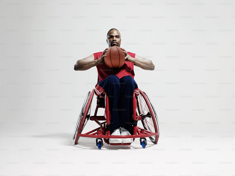 Un uomo su una sedia a rotelle che tiene un pallone da basket