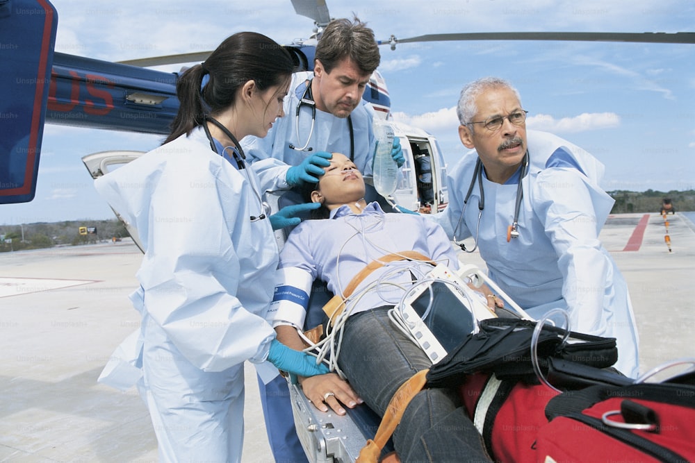Un grupo de personal médico de pie alrededor de una mujer en una camilla