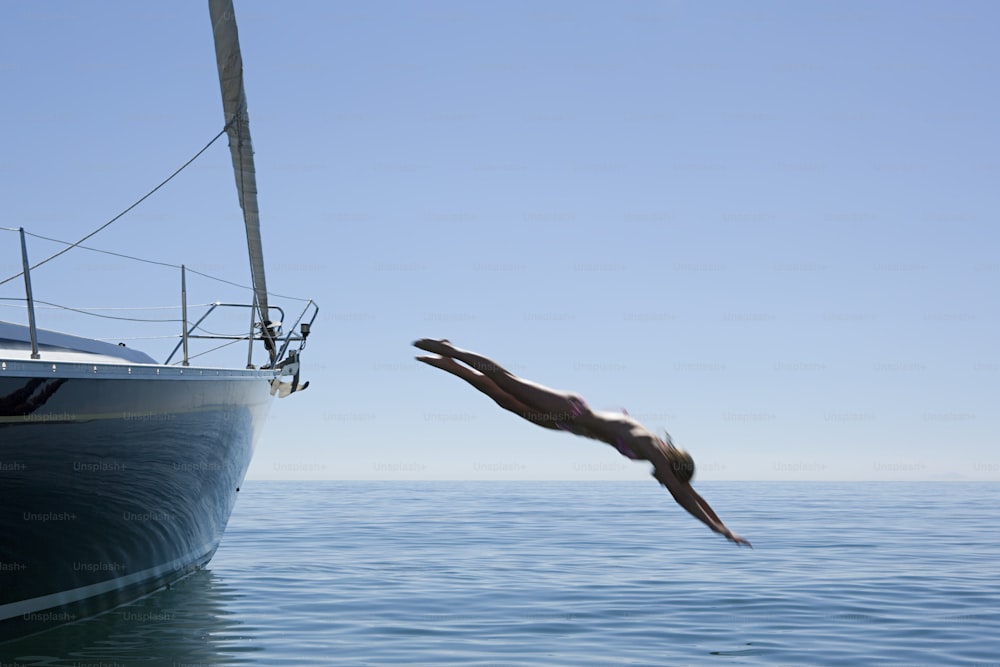 Un hombre se sumerge en el agua desde un barco