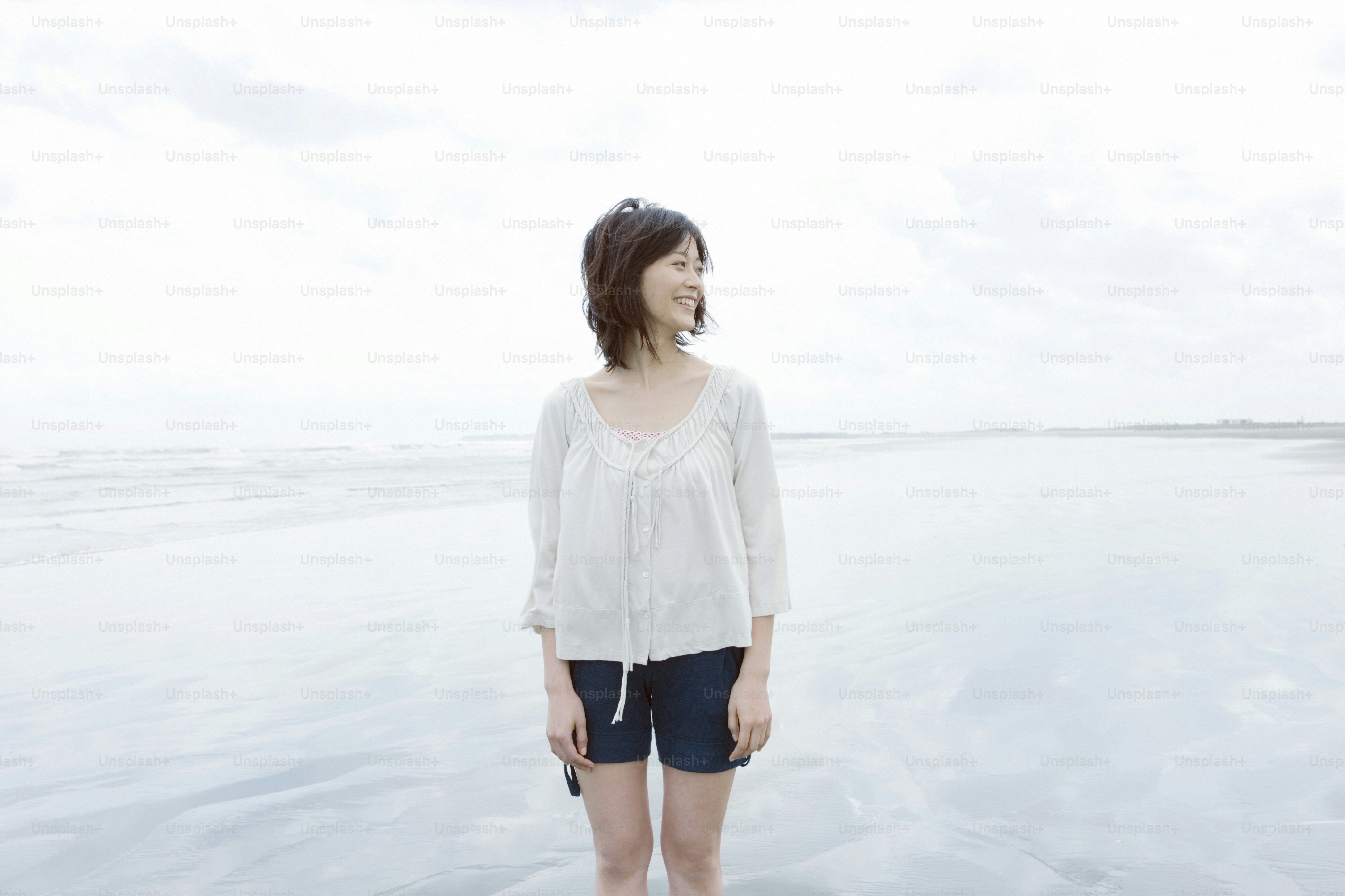 A woman standing on a beach next to the ocean photo – Day Image on Unsplash