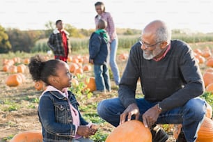 a man and a little girl sitting in a field of pumpkins