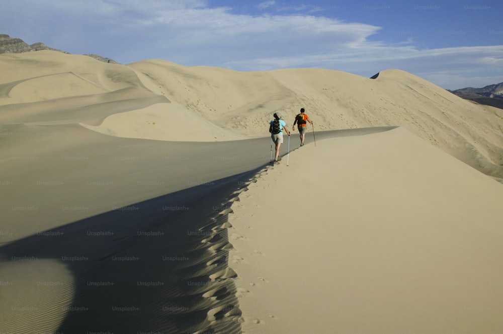 a couple of people that are walking in the sand