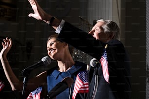 Un hombre y una mujer parados frente a un micrófono