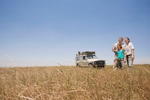 a man and woman standing in a field next to a vehicle