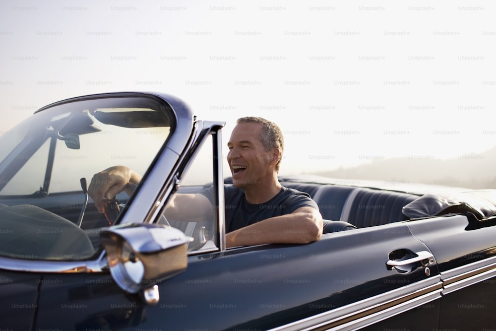 a man sitting in the driver's seat of a classic car