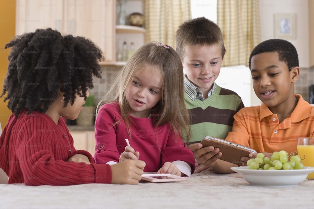 a group of children sitting around a table with food