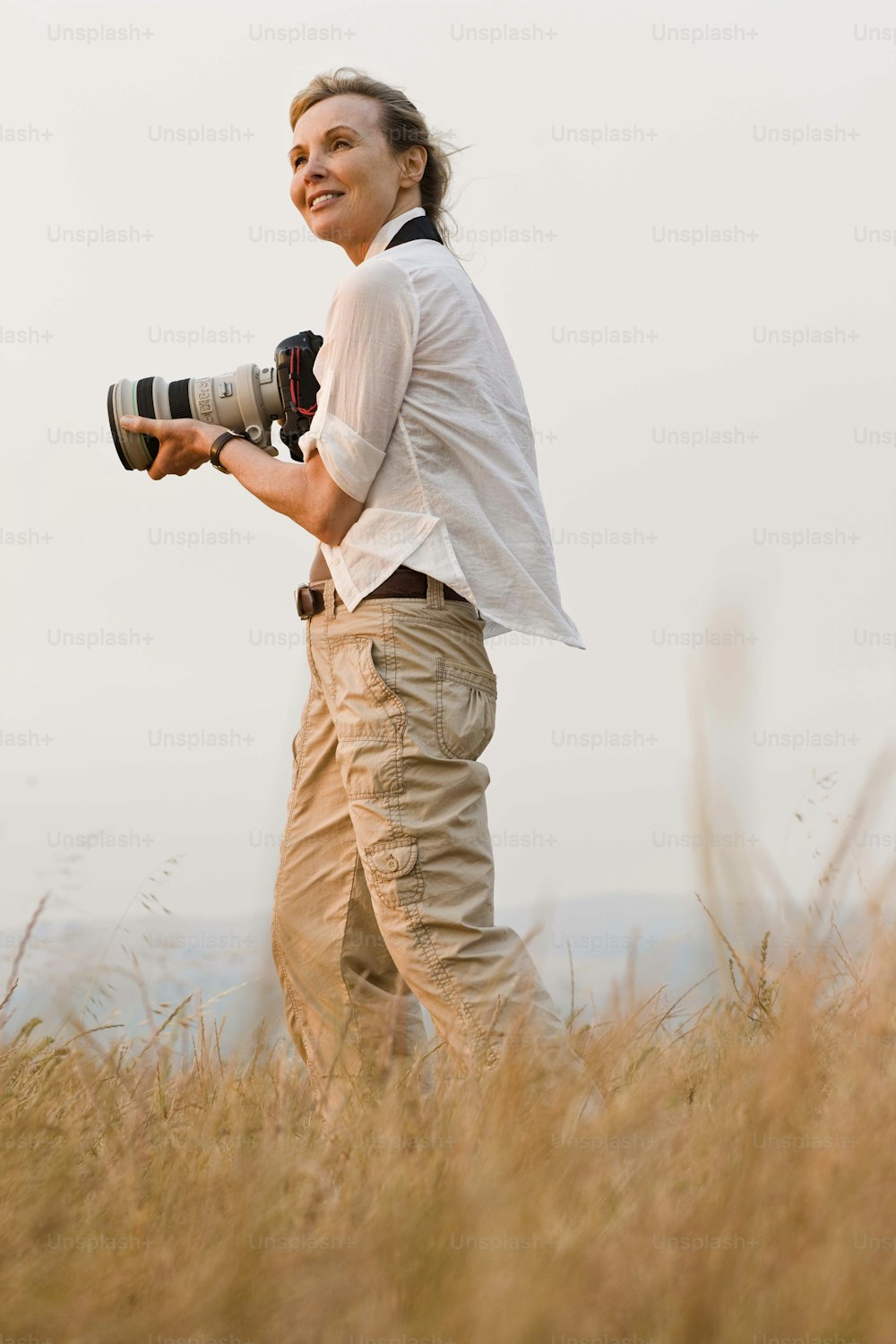 a woman standing in a field holding a camera