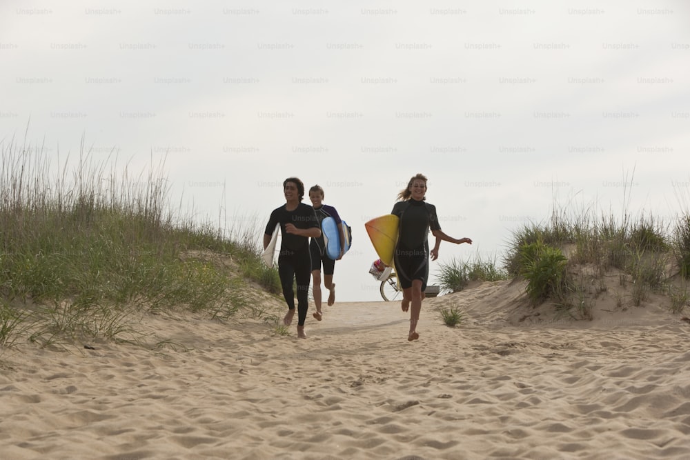 a group of people walking down a beach holding surfboards
