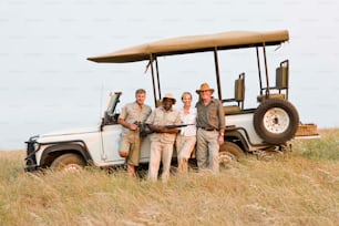 a group of people standing in front of a safari vehicle