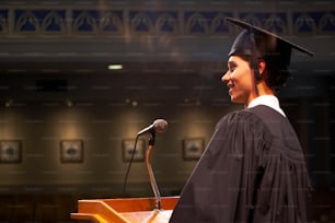 Una donna in un abito di laurea in piedi su un podio