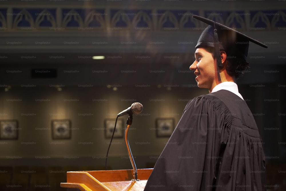 a woman in a graduation gown standing at a podium