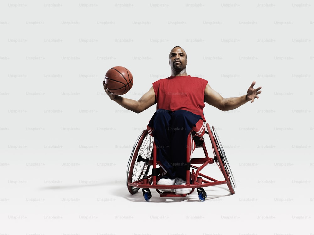 Un uomo su una sedia a rotelle che tiene un pallone da basket