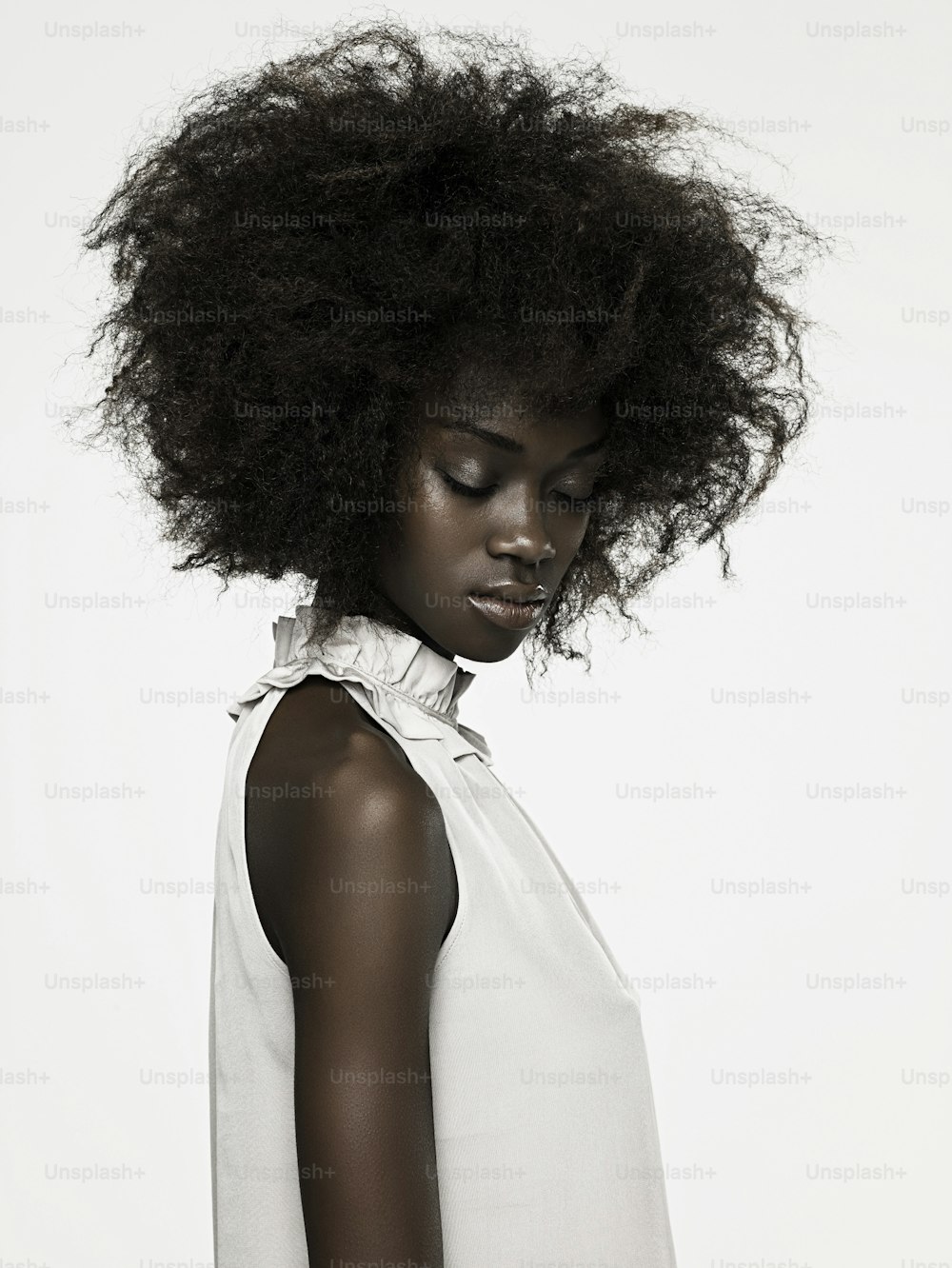 Une femme avec un afro debout devant un fond blanc