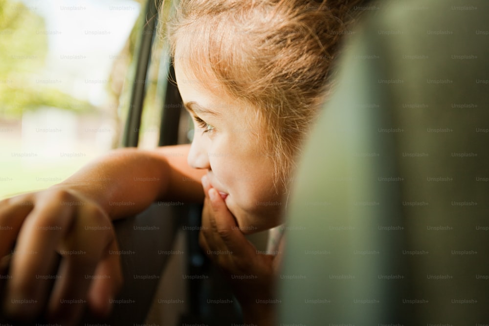 Une jeune fille penchée par la fenêtre d’une voiture