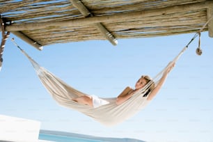 a woman laying in a hammock on the beach