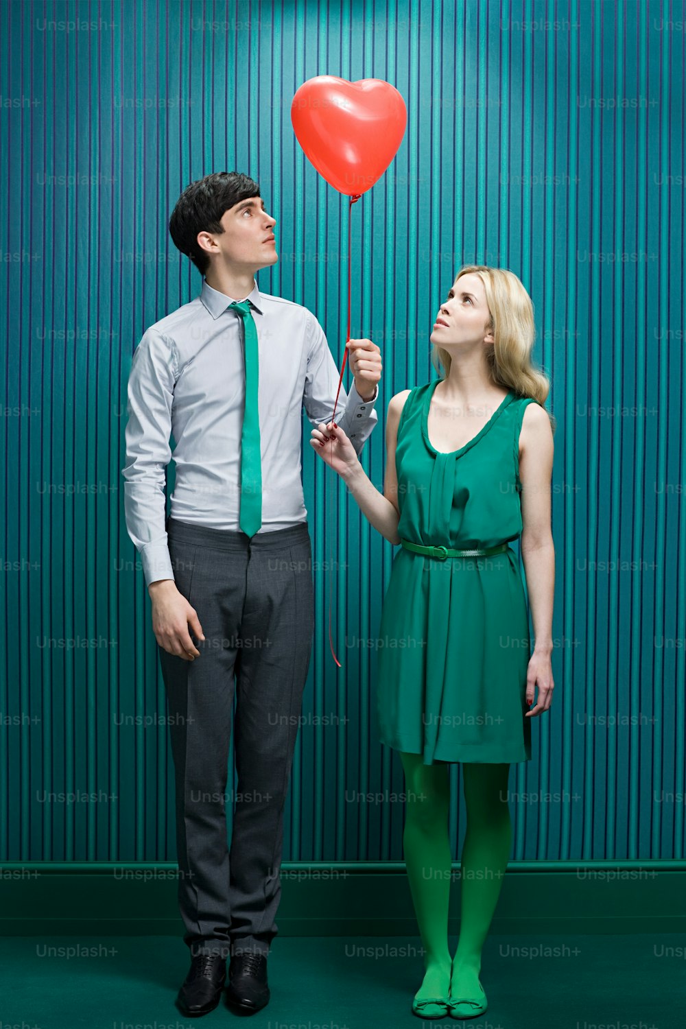 a man and a woman holding a red heart balloon