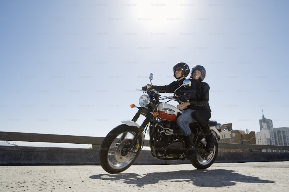 duas pessoas em uma motocicleta em uma ponte