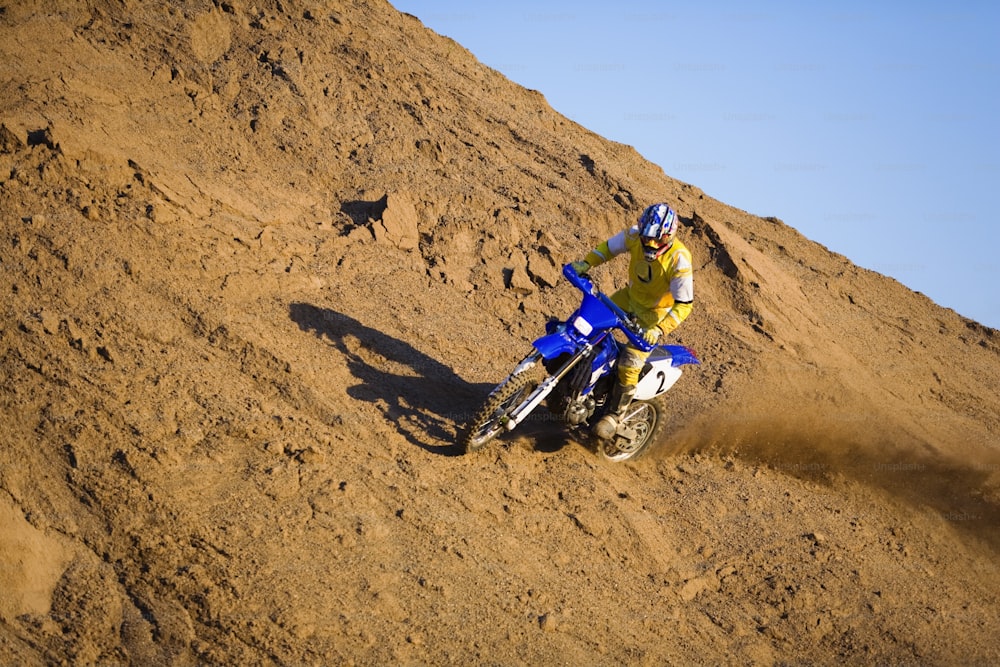 a man riding a dirt bike on top of a dirt hill