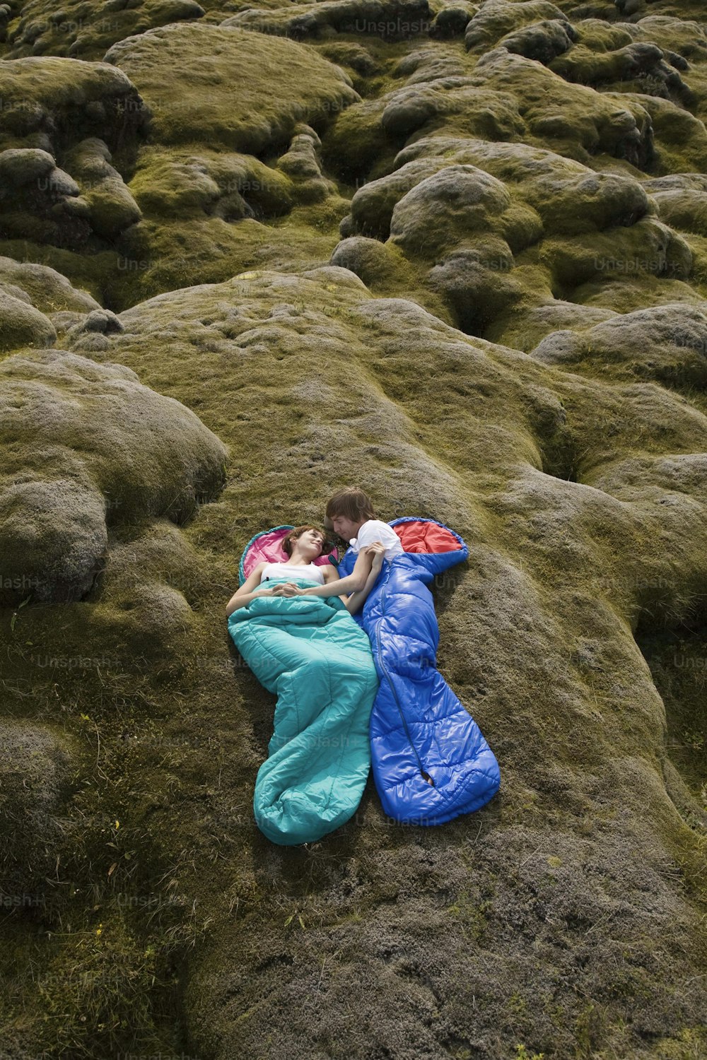 a man and a woman laying on top of a lush green field