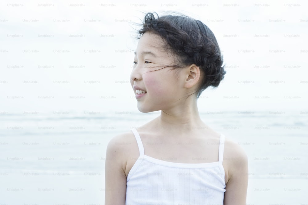 Ein junges Mädchen, das an einem Strand am Meer steht