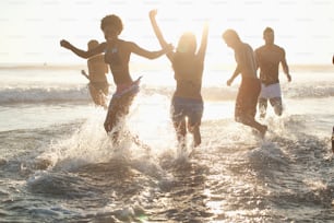 a group of people jumping into the water at the beach