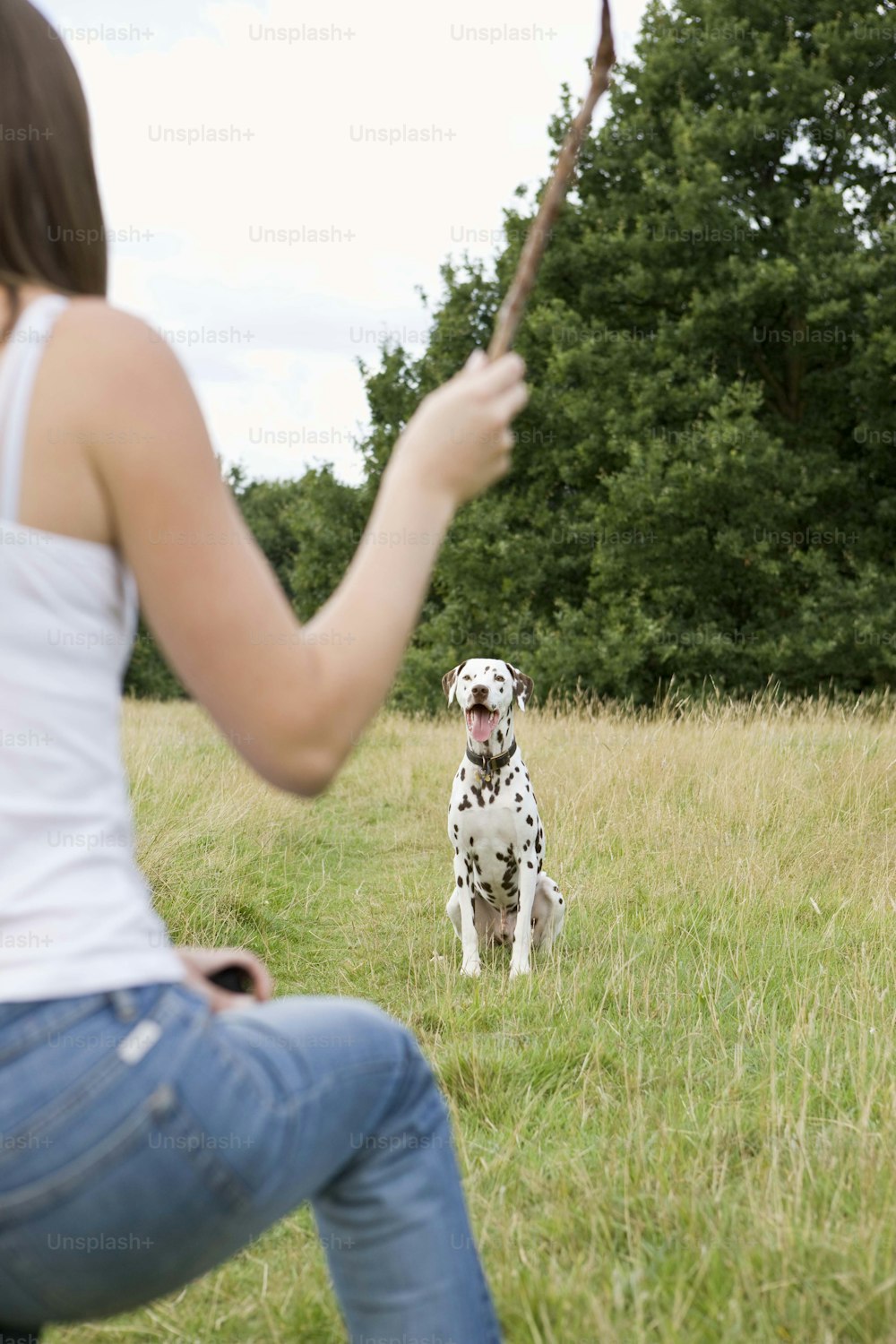 a woman holding a stick in front of a dog