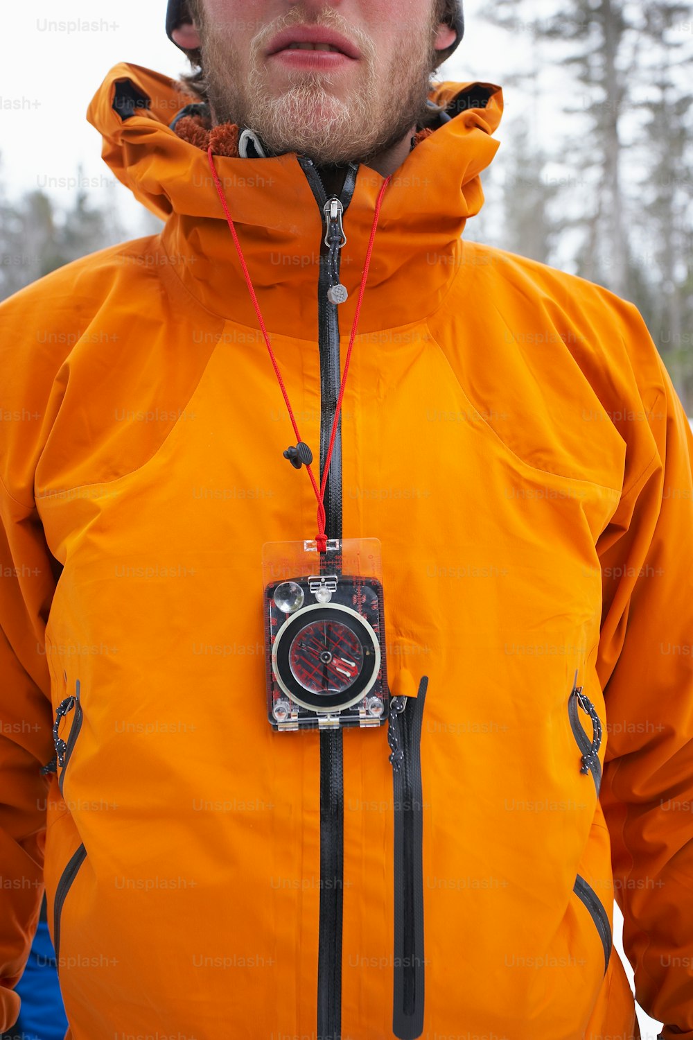 Un homme en veste orange avec une caméra attachée à sa veste