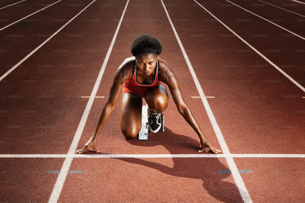 a woman kneeling down on a running track