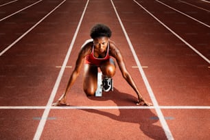 a woman kneeling down on a running track