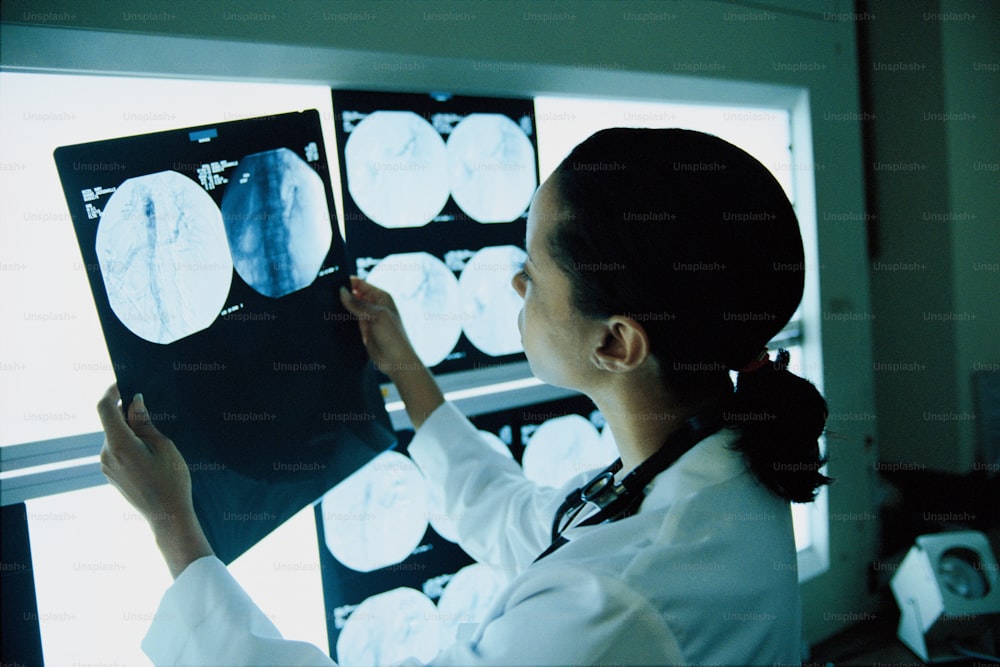 a woman in a white lab coat looking at an x - ray