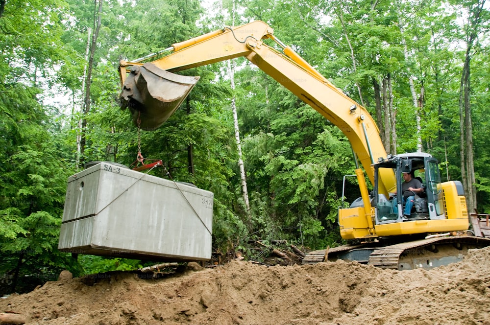 a yellow excavator and a dump truck in a forest